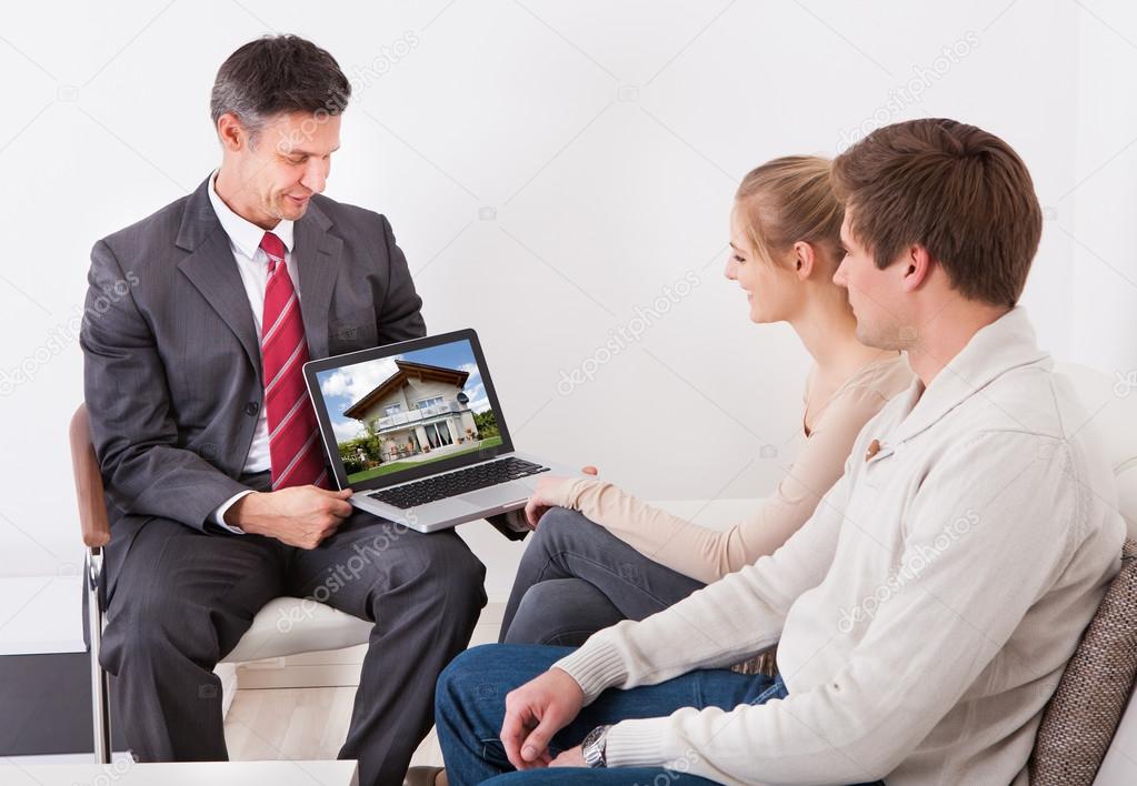 Estate Agent Showing Laptop To Couple