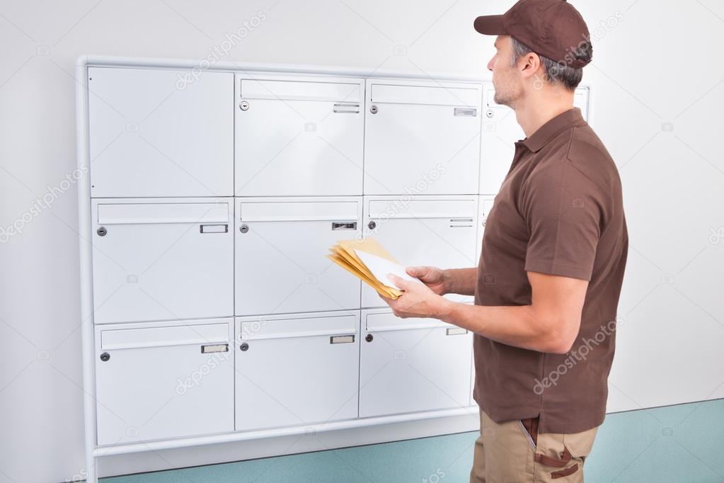 Postman Putting Letters In Mailbox