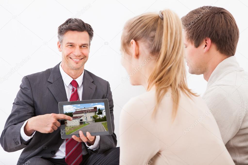 Agent With Tablet Pc Showing House To Couple