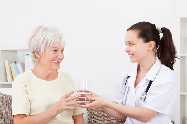 Jeune médecin avec patient tenant verre — Photo