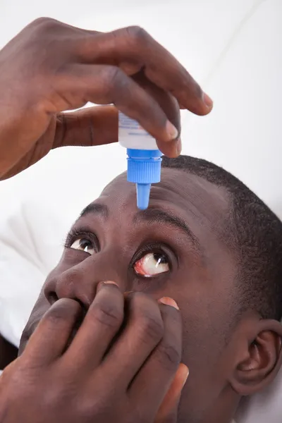 Afrykańskiego człowieka za pomocą zakraplacza do oczu — Zdjęcie stockowe