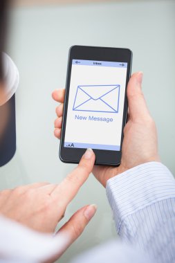 Yeni mesaj işareti ile cep telefonu tutan işadamı