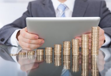 Dijital tablet ve bozuk para yığını ile işadamı
