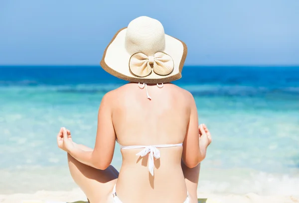 Vrouw in bikini mediteren op kust — Stockfoto