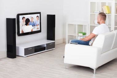 televizyon izlerken onun oturma odasında kanepede oturan adam