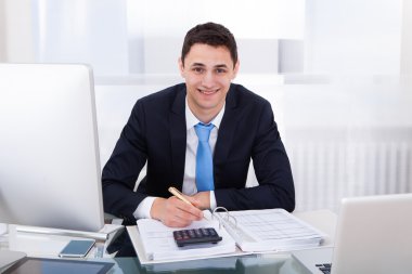 Smiling Businessman Calculating Tax