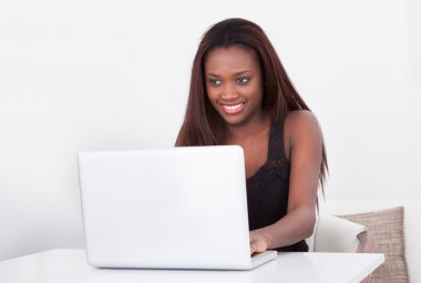 Evde dizüstü bilgisayar kullanan Afrikalı Amerikalı bir kadın.