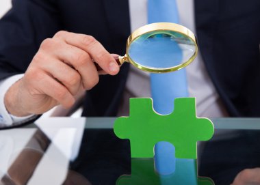 scrutinizing bulmacanın parça büyüteç ile işadamı