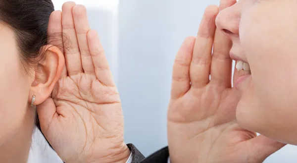 Zakenvrouw in collega's oor fluisteren — Stockfoto