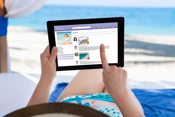 Γυναίκα πλοήγηση στο site κοινωνικής στην παραλία — Stockfoto