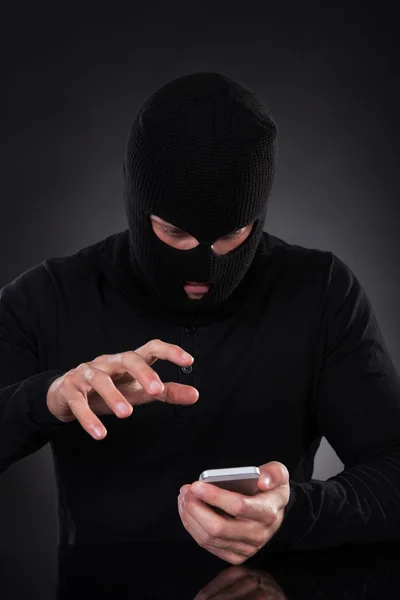 Thief trying to access a stolen mobile phone — Stock Photo, Image