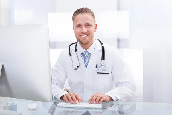 Médecin souriant ou consultant assis à un bureau — Photo