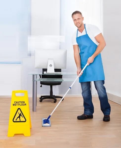 Warning notice as a janitor mops the floor — Stock Photo, Image