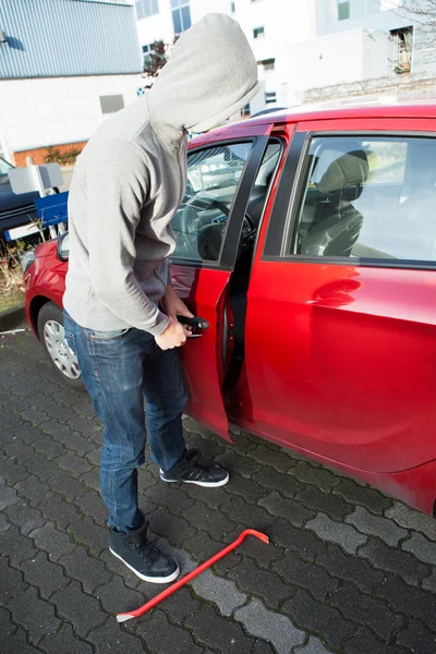 Dief in hooded jas van auto deur — Stockfoto