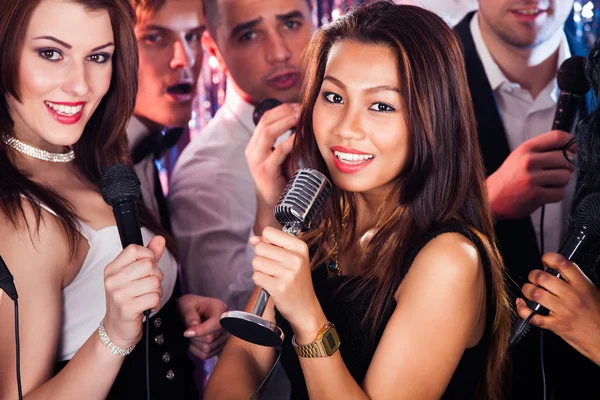Amigos cantando en micrófonos en la fiesta de karaoke —  Fotos de Stock