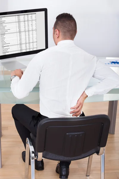Geschäftsmann mit Rückenschmerzen nutzt Computer am Schreibtisch — Stockfoto