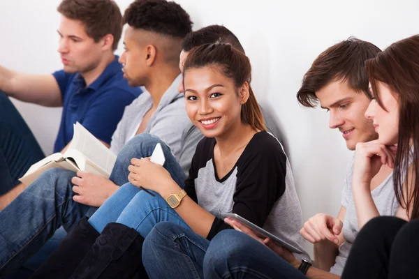 Sorridente studente universitario seduto con i compagni di classe — Foto Stock