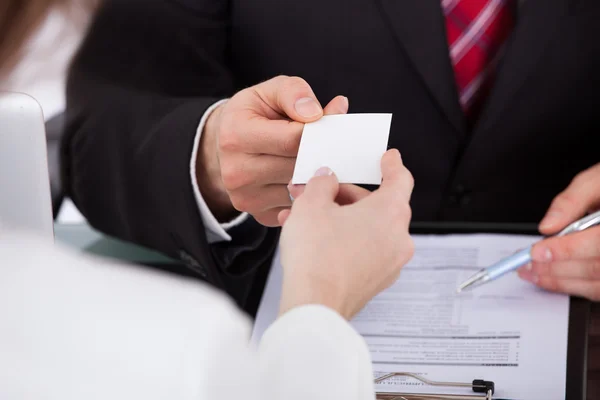 Empresário dando cartão de visita para colegas de trabalho na mesa — Fotografia de Stock
