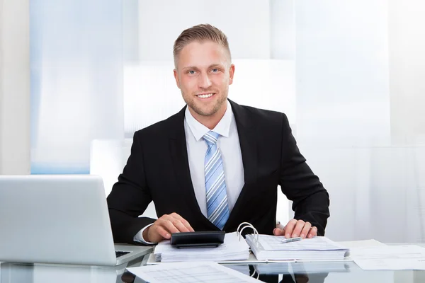 Uśmiechający się biznesmenem st jego biurko — Zdjęcie stockowe