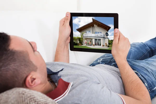 Jonge man nieuw huis op digitale Tablet PC selecteren — Stockfoto