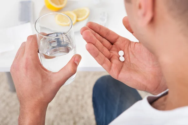 Chory człowiek biorąc tabletki z szklanką wody — Zdjęcie stockowe