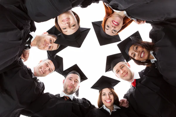 Estudiantes graduados de pie en círculo inclinados hacia la cámara — Foto de Stock