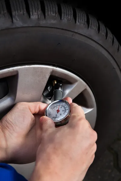 タイヤの空気圧のゲージを使用してチェックするメカニック — ストック写真