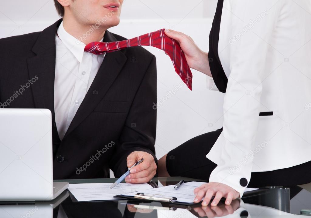 Businesswoman Pulling Male Colleague's Tie While Seducing Him