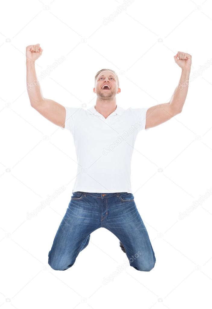 Excited man cheering in jubilation dropping down on his knees
