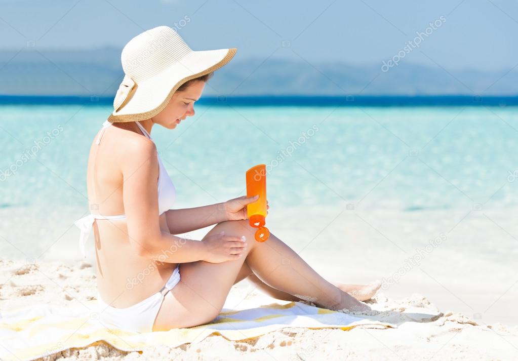 Woman in bikini applying sunscreen