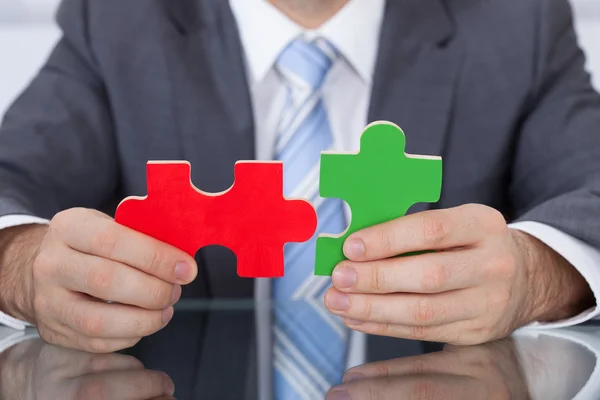Uomo d'affari Montaggio due pezzi puzzle insieme — Foto Stock