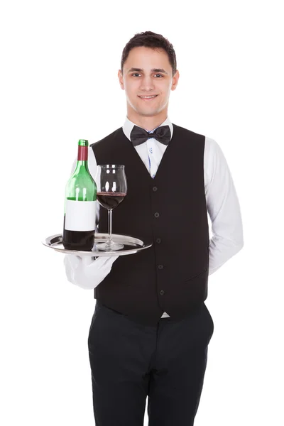 Garsona kırmızı şarap ve şişe cam tepsiye holding — Stok fotoğraf