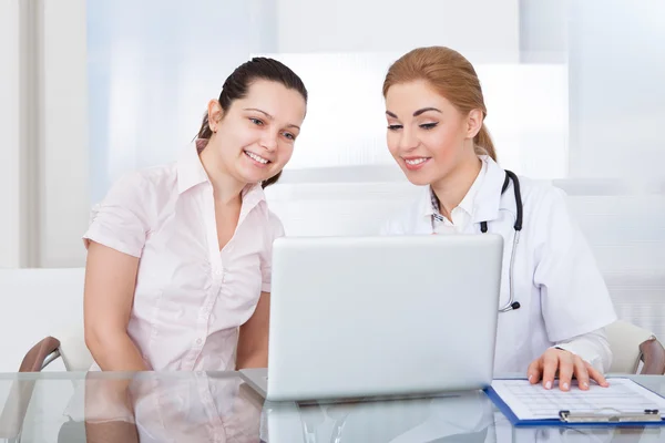 Medico e paziente guardando il computer portatile — Foto Stock
