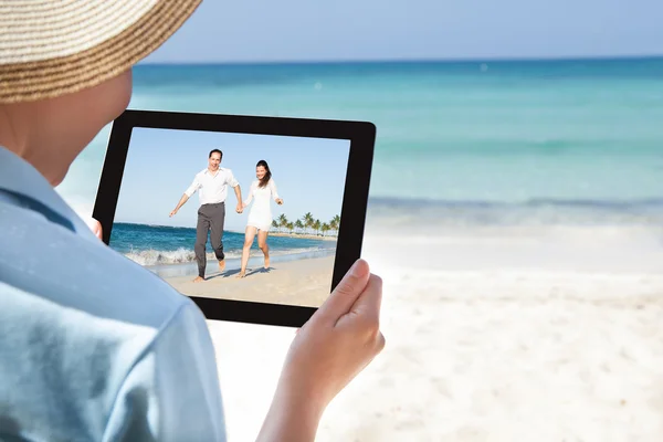 Женщина смотрит видео на цифровом планшете на пляже — стоковое фото