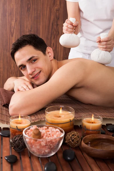 Hombre recibiendo masaje con sellos en spa — Foto de Stock