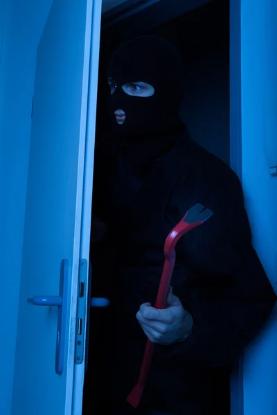 Ladrão segurando Crowbar enquanto entra em casa — Fotografia de Stock