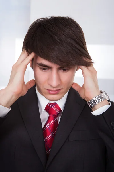 Uomo d'affari che soffre di mal di testa durante il calcolo della finanza — Foto Stock