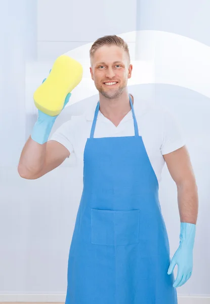 Αρσενικό επιστάτης χρησιμοποιώντας ένα σφουγγάρι για να καθαρίσετε ένα παράθυρο — Φωτογραφία Αρχείου