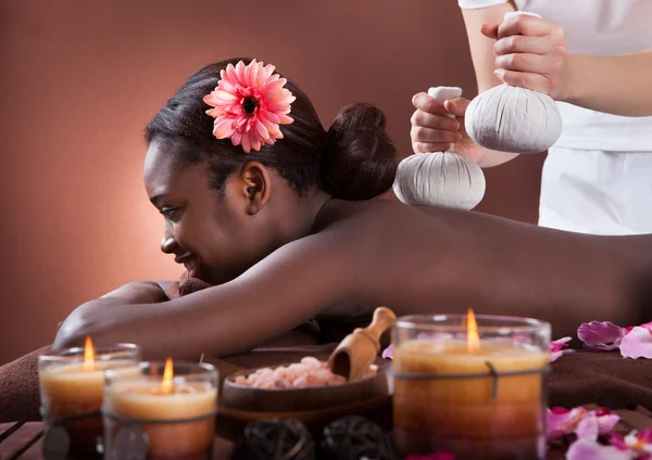 African American woman enjoying herbal massage at spa salon — Stock Photo, Image
