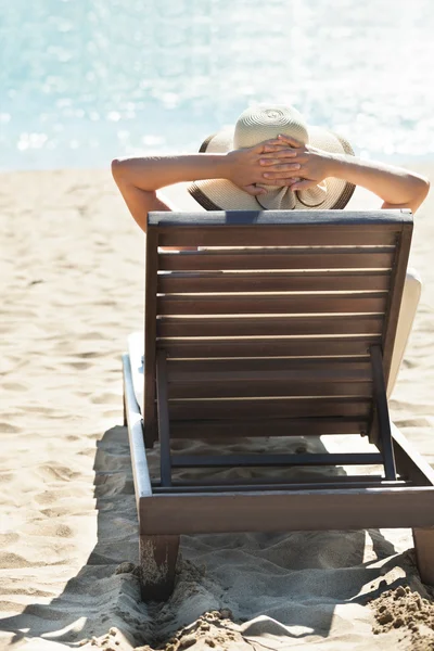 Kvinna avkopplande på solstol på tropical beach — Stockfoto