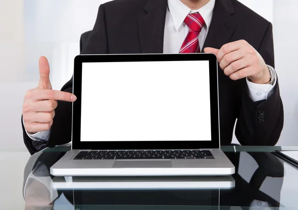 Selbstbewusster Geschäftsmann zeigt Laptop am Schreibtisch — Stockfoto