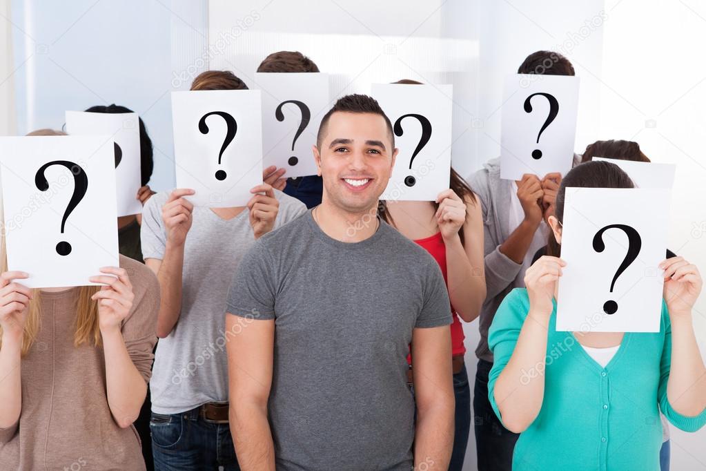 Student Surrounded By Classmates Holding Question Mark Signs