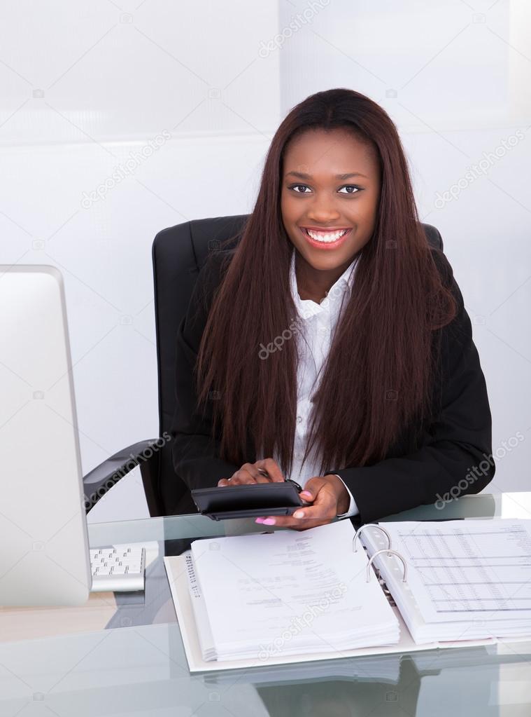 Confident Businesswoman Calculating Tax At Desk