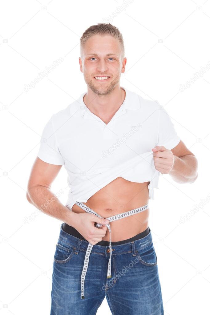 Healthy fit young man lifting up his white t-shirt