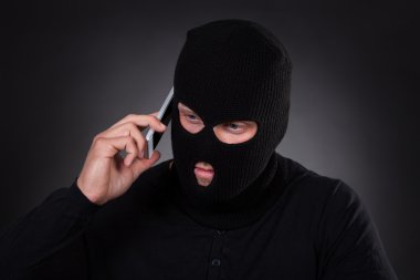 Thief using a stolen mobile phone clipart
