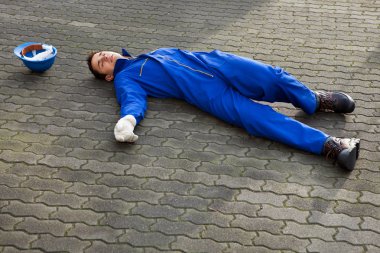 Unconscious Repairman In Uniform Lying On Street clipart