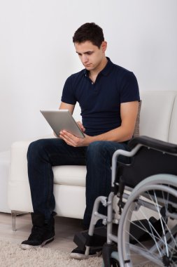Handicapped Man Using Digital Tablet On Sofa clipart