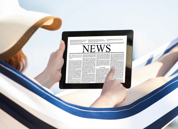 해먹에서 디지털 태블릿에 신문을 읽는 여자 — 스톡 사진