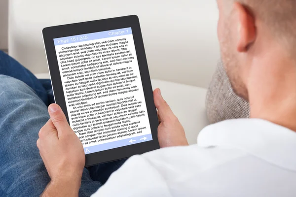 Чоловік розслабляється вдома читає електронну книгу онлайн — стокове фото