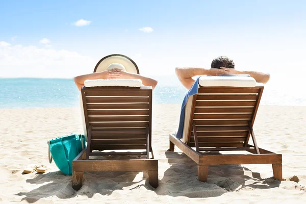 Pareja relajándose en tumbonas en el resort de playa —  Fotos de Stock